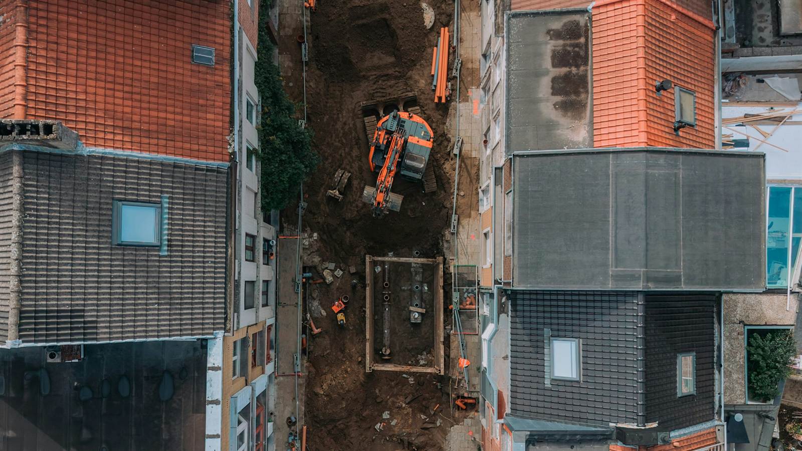Excavator working in a narrow construction site between urban buildings