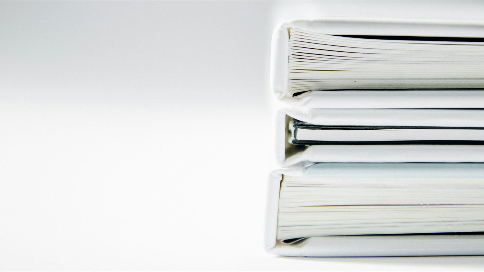 Three thick document folders stacked on a white surface.