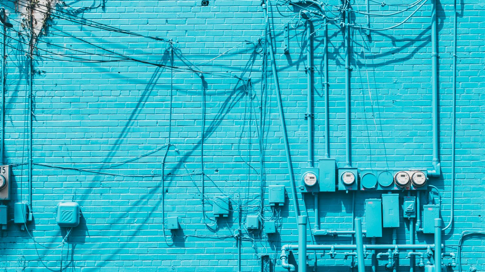 Utility meters and conduit on a turquoise wall