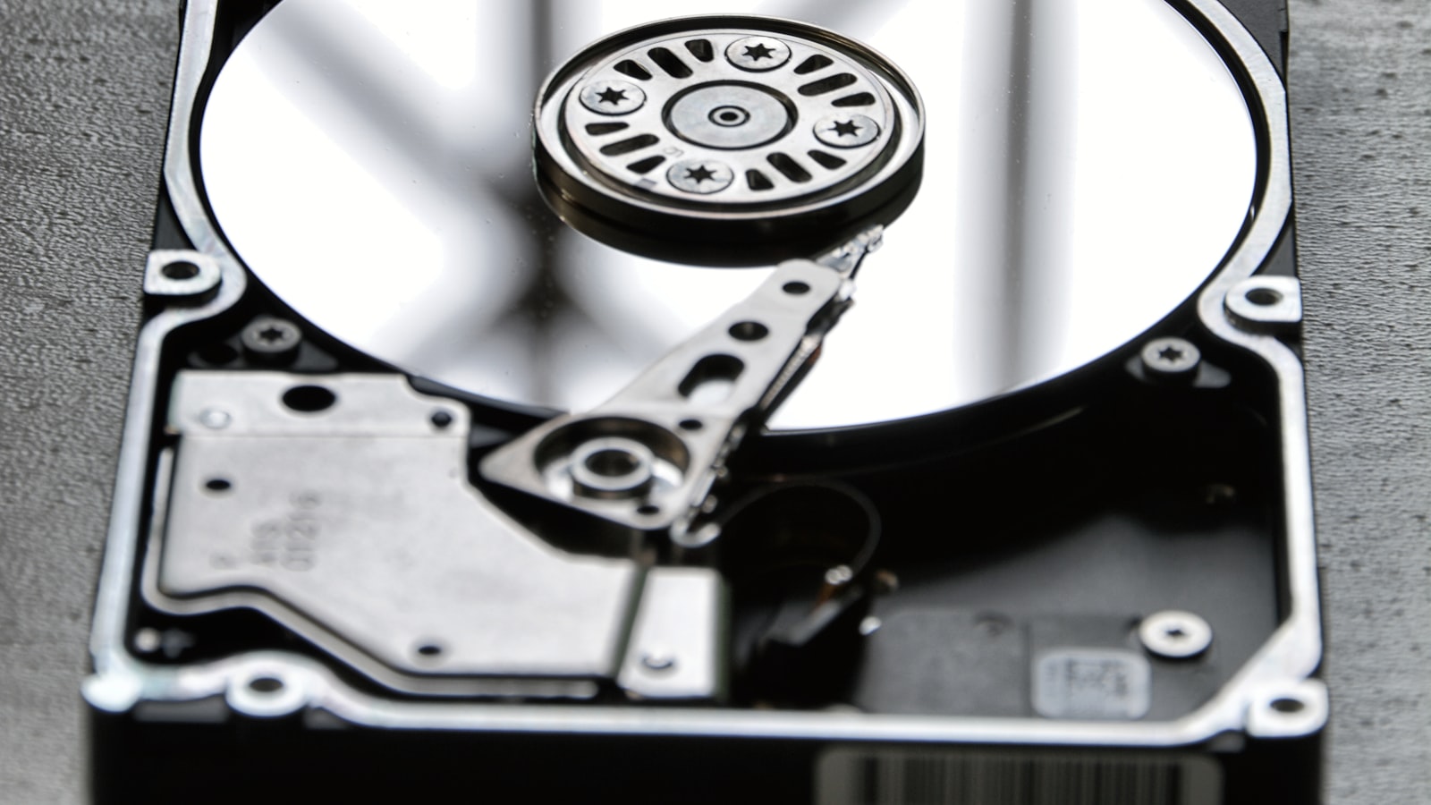 Open hard disk drive with its reflective platter exposed